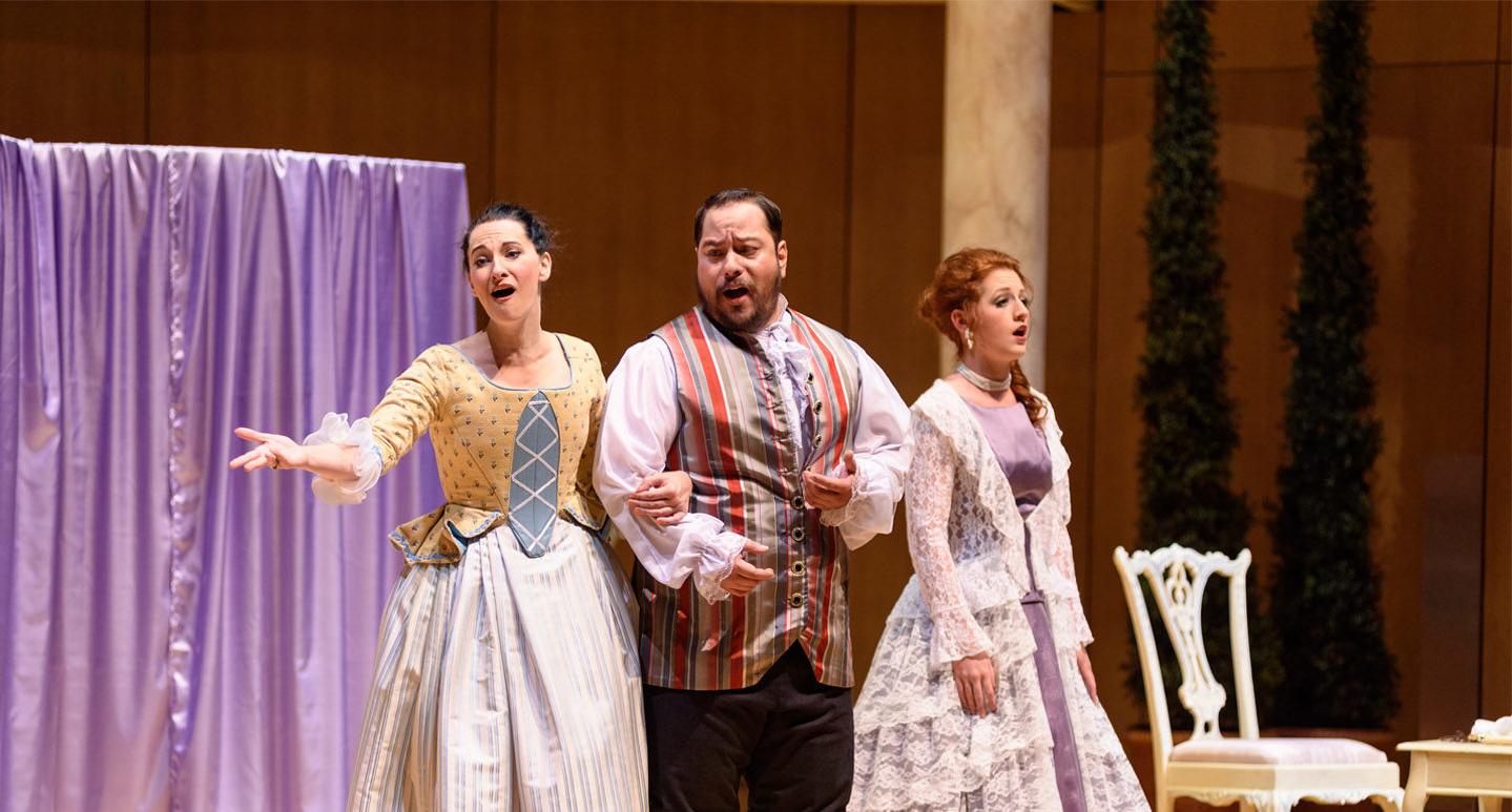 Three opera singers on stage performing Figaro in period costume